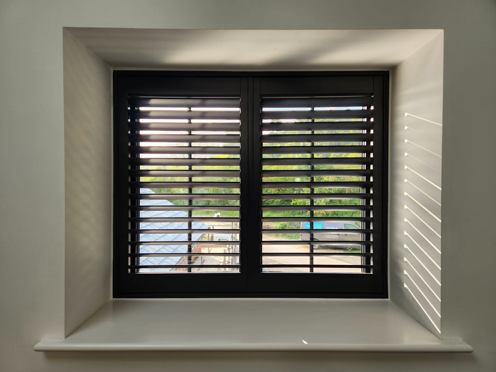 Black wood shutters in a deep window reveal