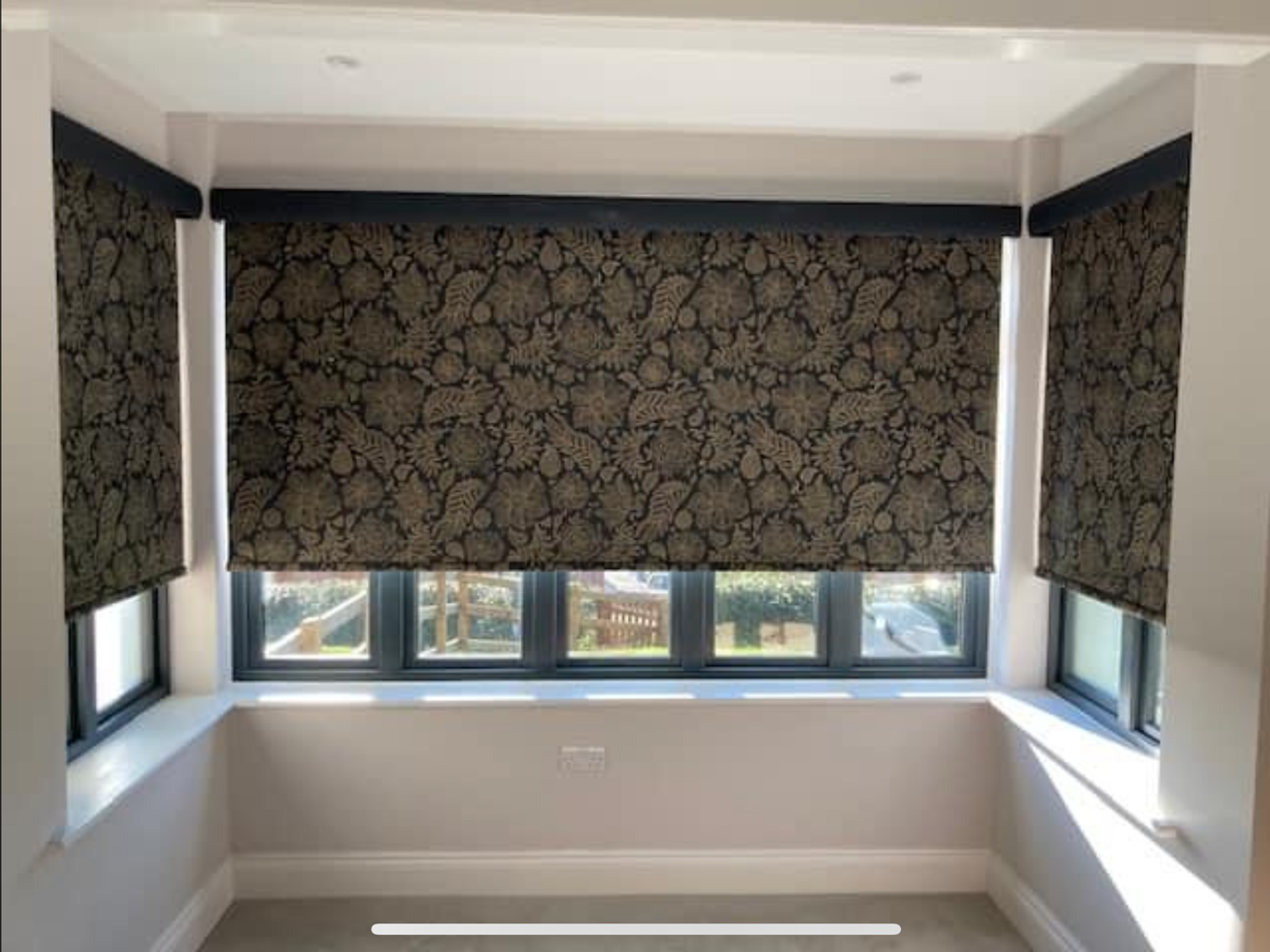 Pelmet covered roller blinds across a bay window